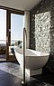 Nybygget badeværelse med udsigt. Klinker af skifer på gulvet og rå granit på væggen.